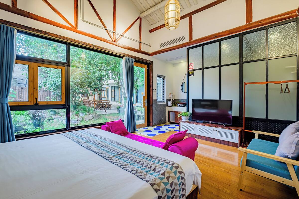 Un dormitorio con una cama grande, televisión y escritorio.