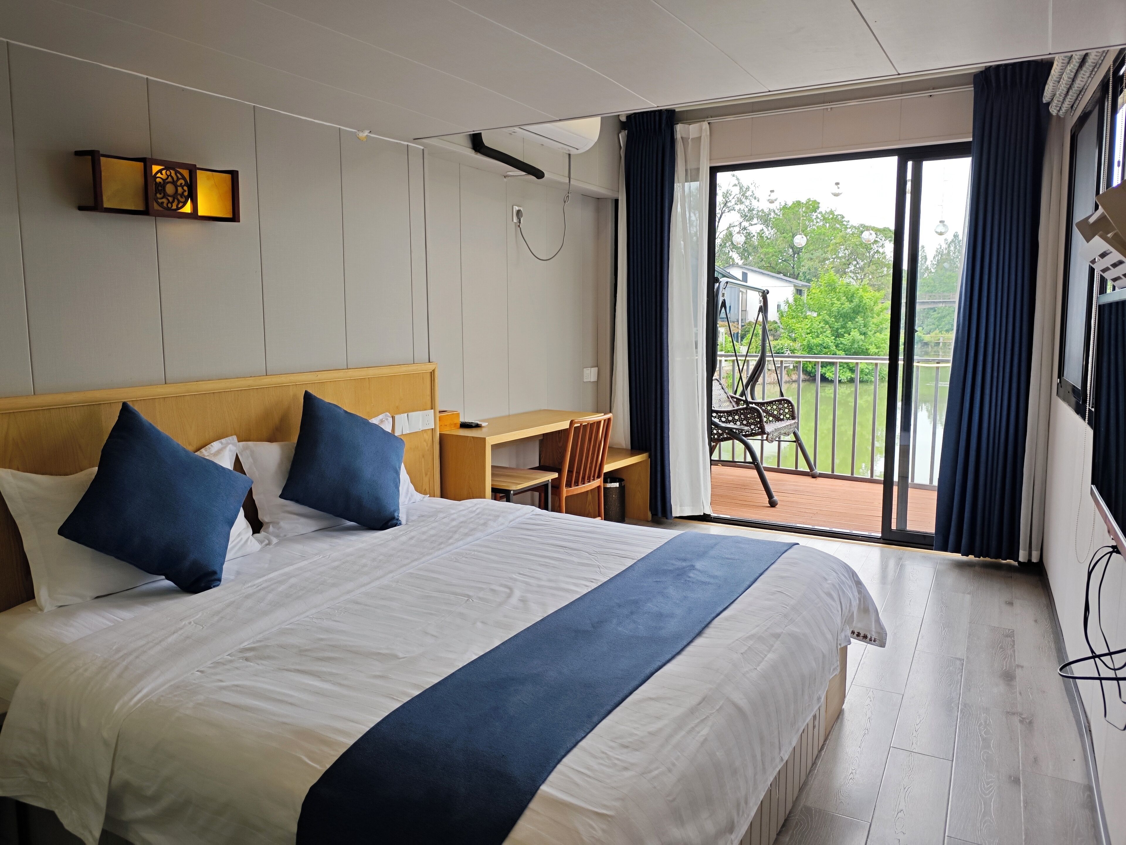 A hotel room with a large bed, a desk, and a view of the outdoors.