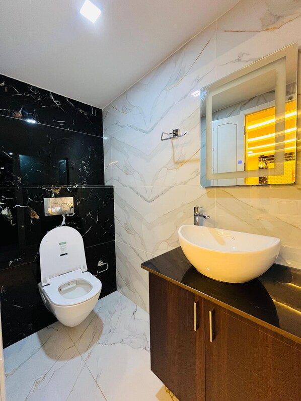 Un baño moderno con inodoro, tocador y un espejo grande.