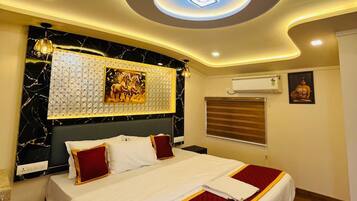 A hotel room with a bed, a ceiling light, a wall-mounted air conditioner, and a window with blinds.