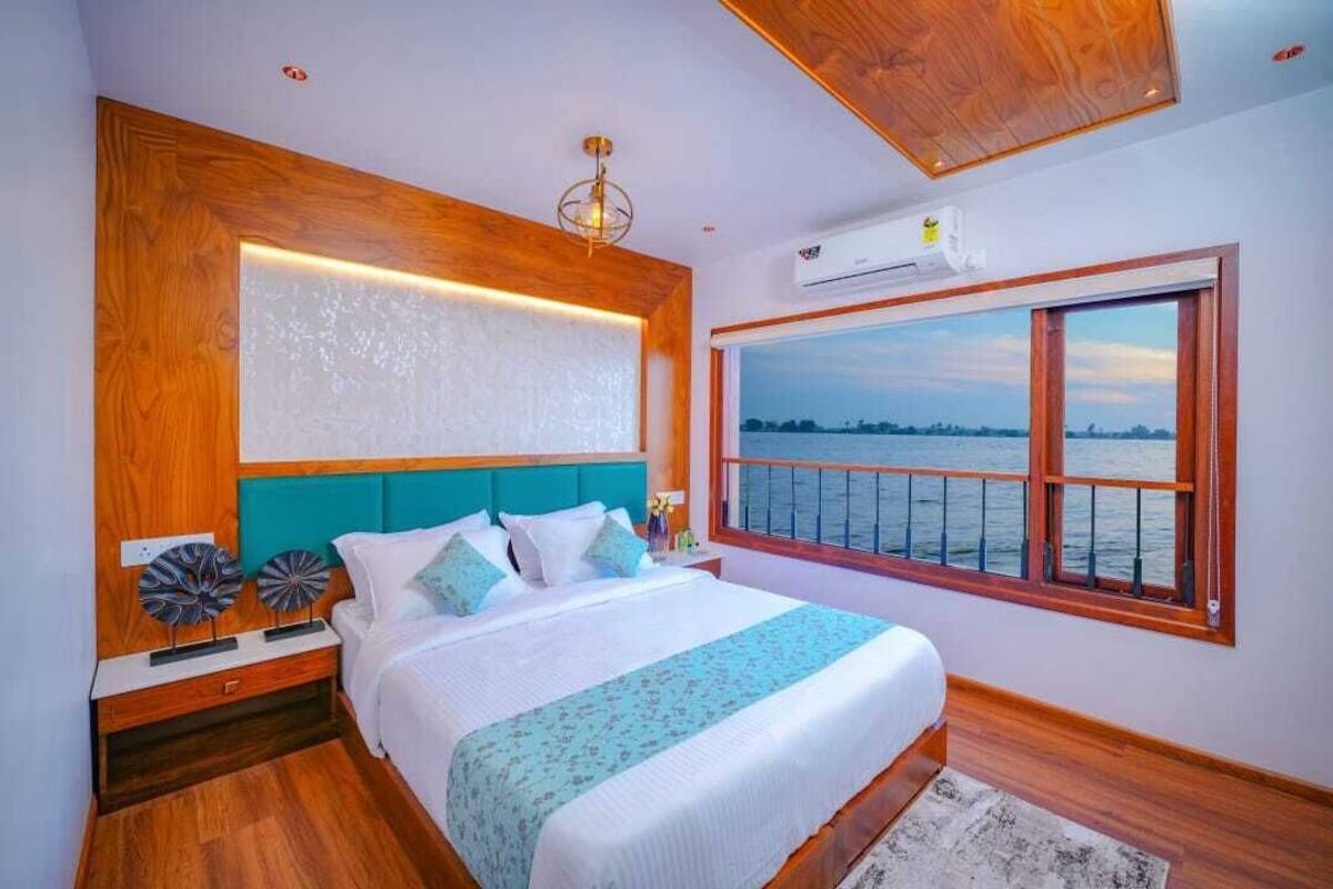 A bedroom with a large bed, a view of the water, and a wooden ceiling.