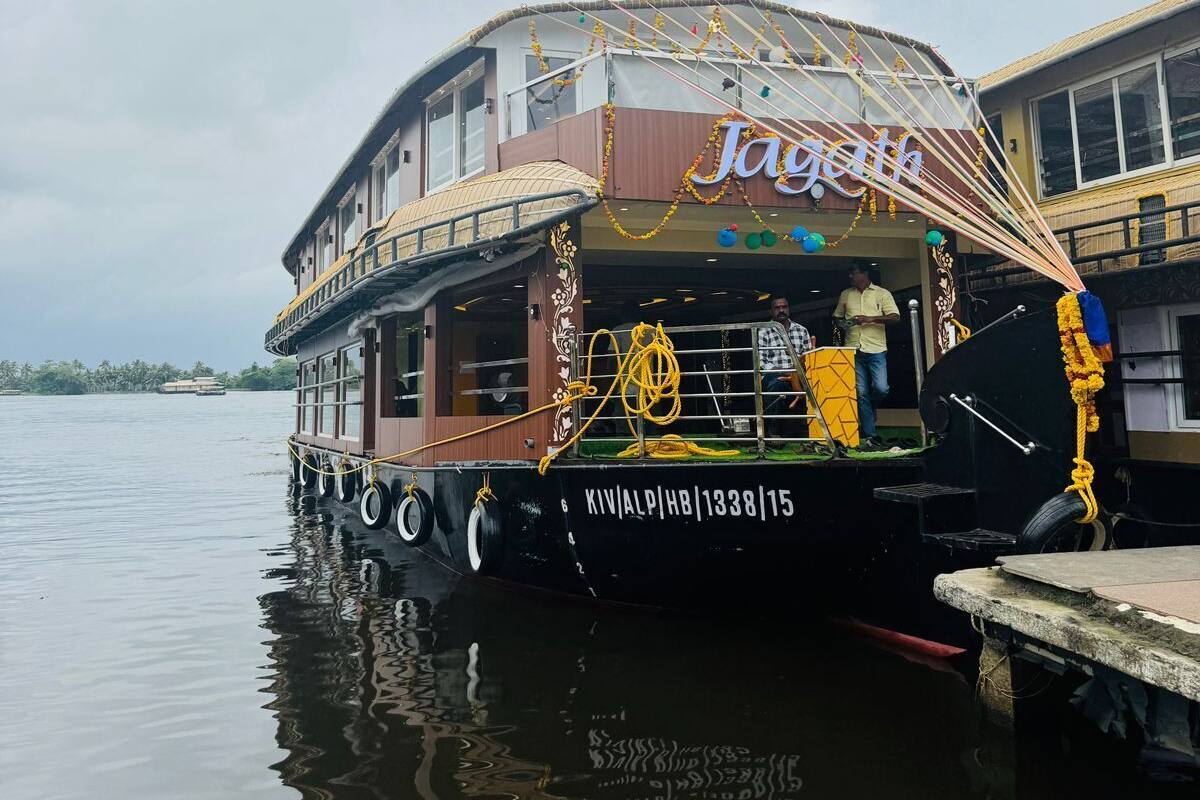 A houseboat with a sign reading "Jayachith" docked at a pier.