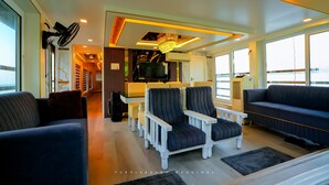 A modern living room with a sofa, armchairs, and a TV. - Beachparadise  Daycruise houseboat (Ambalapuzha)