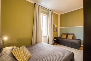 A bedroom with a bed, bedside table, and a dresser.
