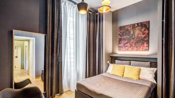 Une chambre à coucher moderne avec un grand lit, une chaise, un miroir et un tableau accroché au mur.