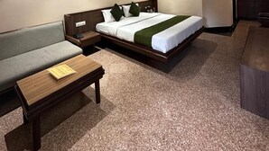 Une chambre d’hôtel avec un lit, un canapé, une table en bois et un bureau.