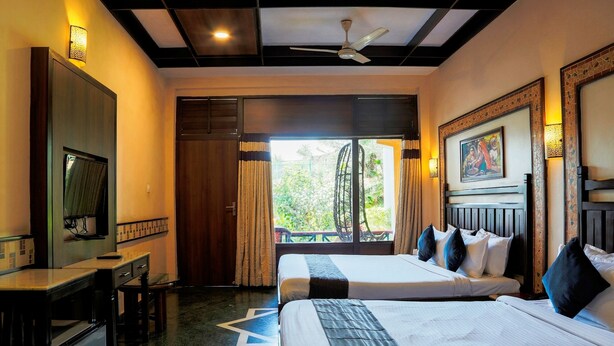 Une chambre d’hôtel avec deux lits, un bureau, une télévision et une vue sur la verdure environnante.