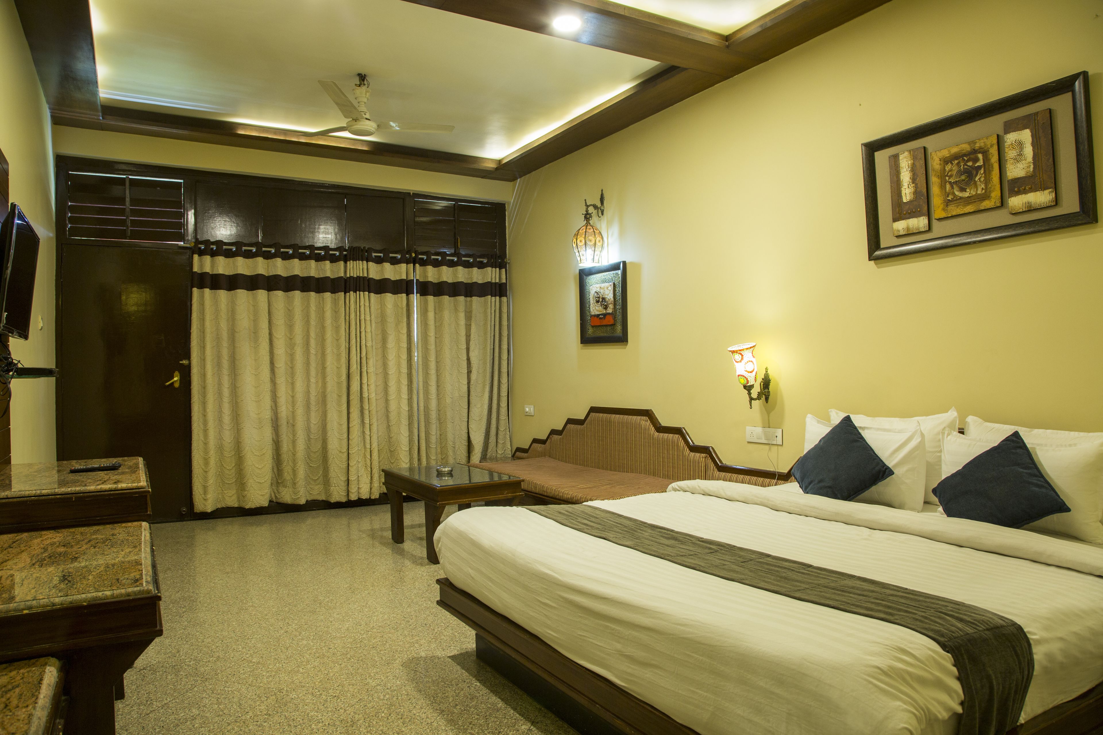 A hotel room with a bed, a desk, a chair, a wardrobe, and a curtain.