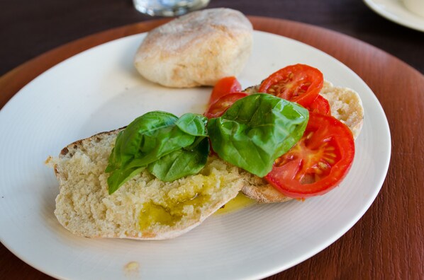 Une assiette avec un sandwich, des tranches de tomate et des feuilles de basilic.