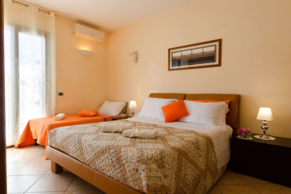 A hotel room with two beds, a nightstand with a lamp, and a framed picture on the wall.
