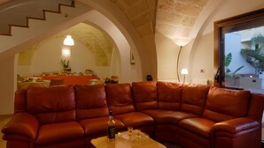 A spacious living area with a brown leather sectional sofa, a coffee table, and a dining area with a table and chairs. - B&B L'Antica Rimessa (Lecce)