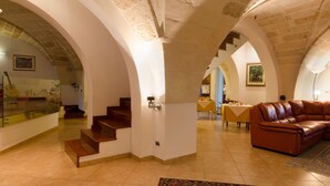 A spacious interior with a staircase, a leather sofa, and a dining area. - B&B L'Antica Rimessa (Lecce)