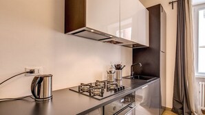 A modern kitchen with a stainless steel kettle, a gas stove, and a coffee maker on the counter. - Cinque Terre Decor (La Spezia)