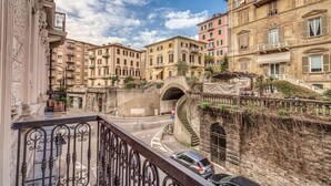 Une vue de rue avec un pont en pierre, des bâtiments dotés de balcons et un ciel dégagé.