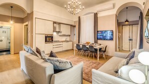 Un salon moderne comprenant un canapé, une table à manger avec des chaises, un coin cuisine et un téléviseur fixé au mur.