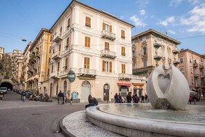 A public square with a fountain, historic buildings, and a sign for "Banane Ristorante."
