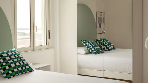 A bedroom with a bed, a window, and a mirror. - Spacebility Airport-  self check-in (Cagliari)