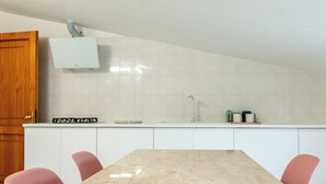 A kitchen with white cabinets, a marble countertop, and a wooden door. - Spacebility Airport-  self check-in (Cagliari)