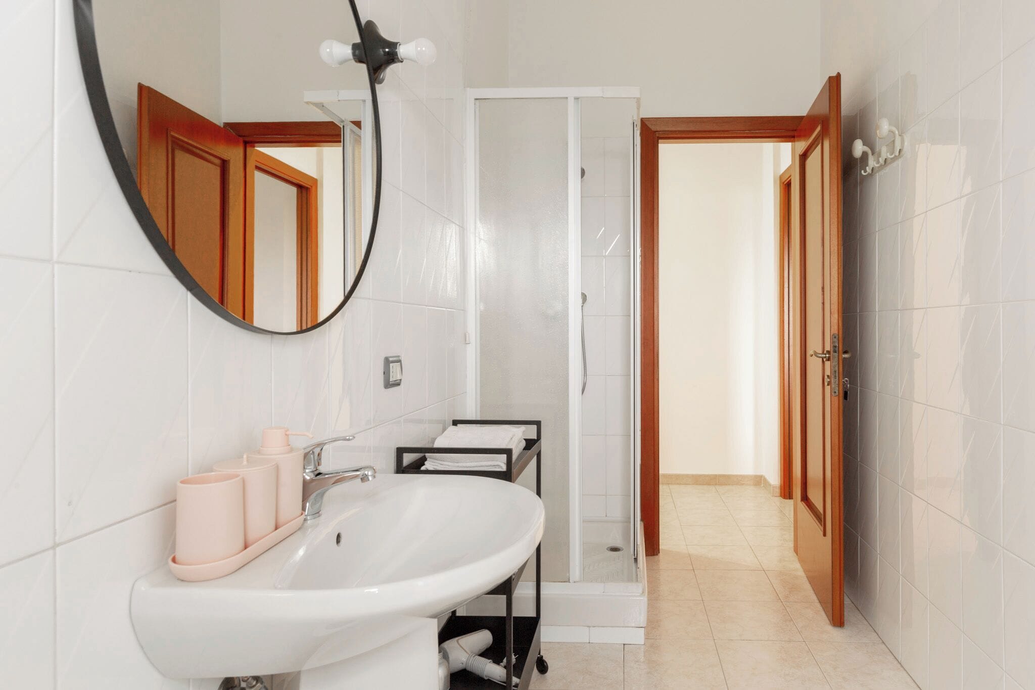 A modern bathroom with a white sink, mirror, and shower.