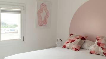 Un dormitorio con cama, un ventanal grande y una obra de arte colgada en la pared.