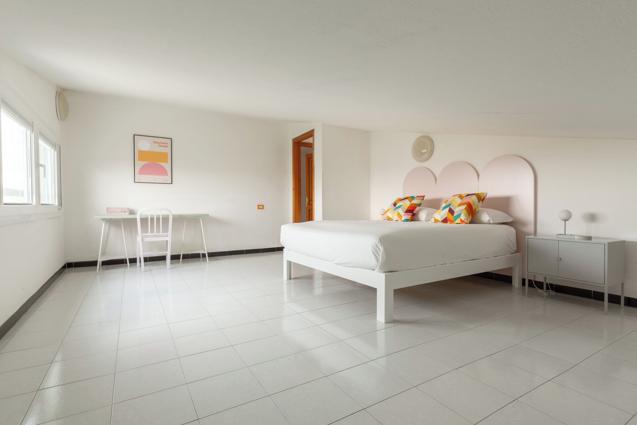 Une chambre à coucher comprenant un lit, une table de chevet, une chaise et un petit bureau.