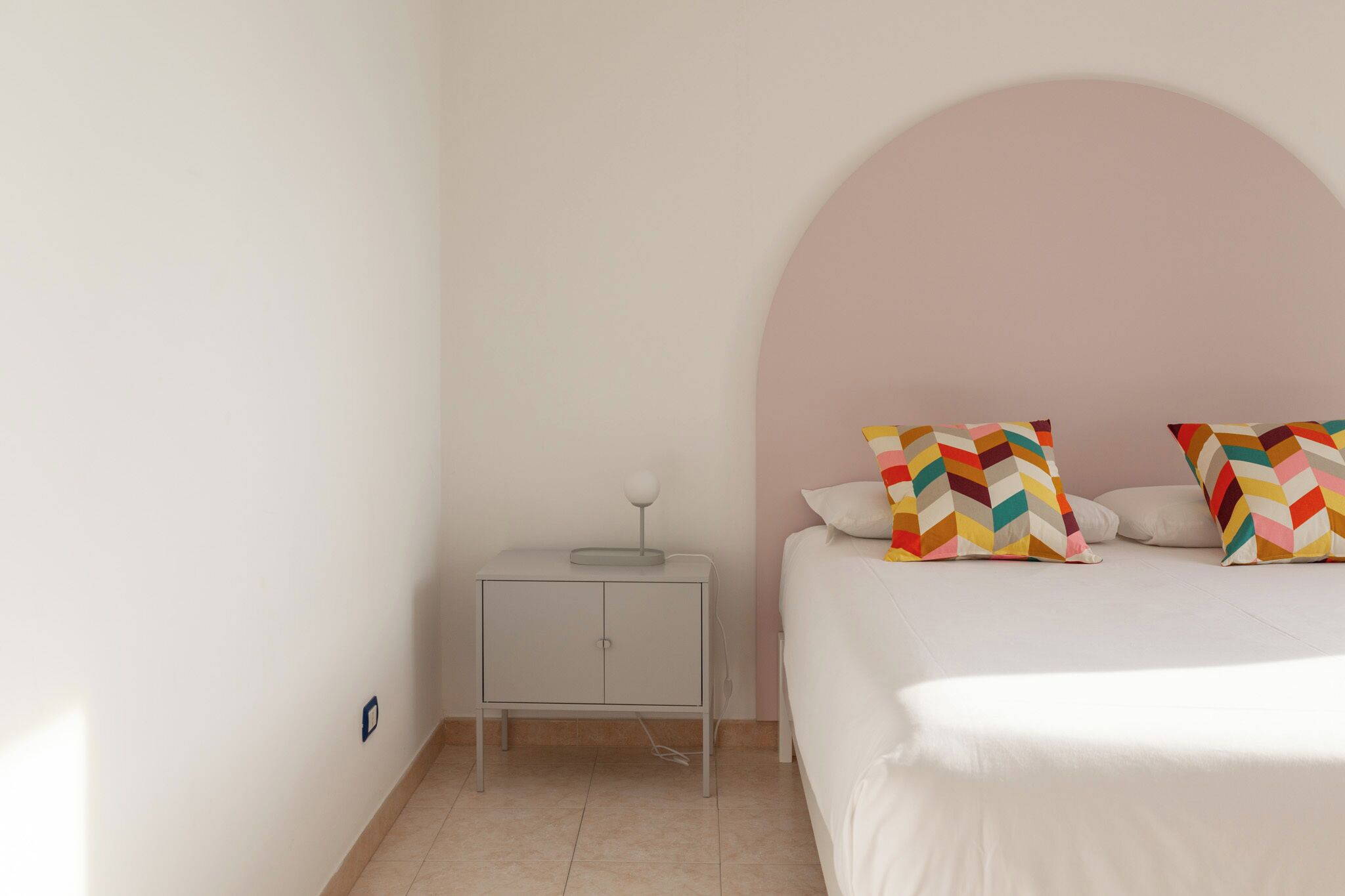 Une chambre à coucher avec un lit, une table de chevet et une arche murale.