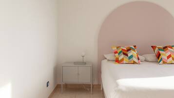 Un dormitorio con cama, mesita de noche y un arco en la pared.