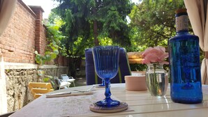 Una mesa con un vaso azul, un florero rosa y una botella azul.