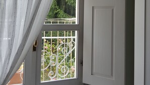 Una habitación con ventana que tiene una reja metálica blanca y una cortina blanca.