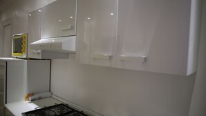 A kitchen with a stove, white cabinets, and a microwave. - Blanco Vaticano (Rome)