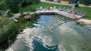 Una piscina con zona de solarium, rodeada de follaje.