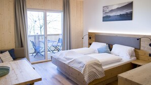 Un dormitorio con una cama grande, cabecera de madera, una mesa de comedor y un balcón con sillas.
