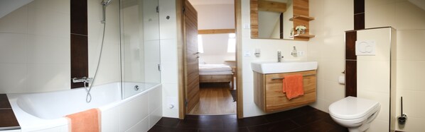 Une salle de bain moderne équipée d’une baignoire, d’une douche, de toilettes et d’un meuble-lavabo avec un miroir.