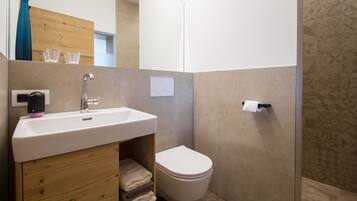 A modern bathroom with a white sink, a toilet, and a mirror.