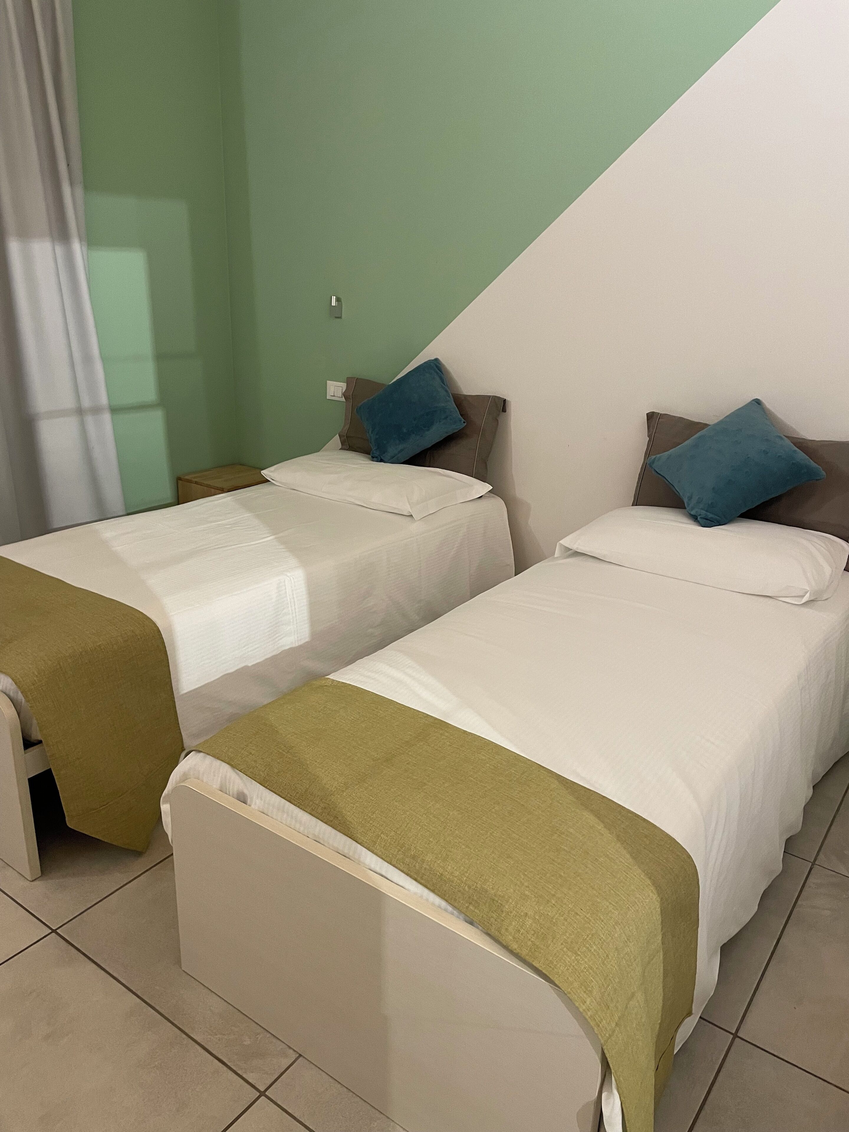 Una habitación de hotel con dos camas individuales, cada una con una almohada y una manta.