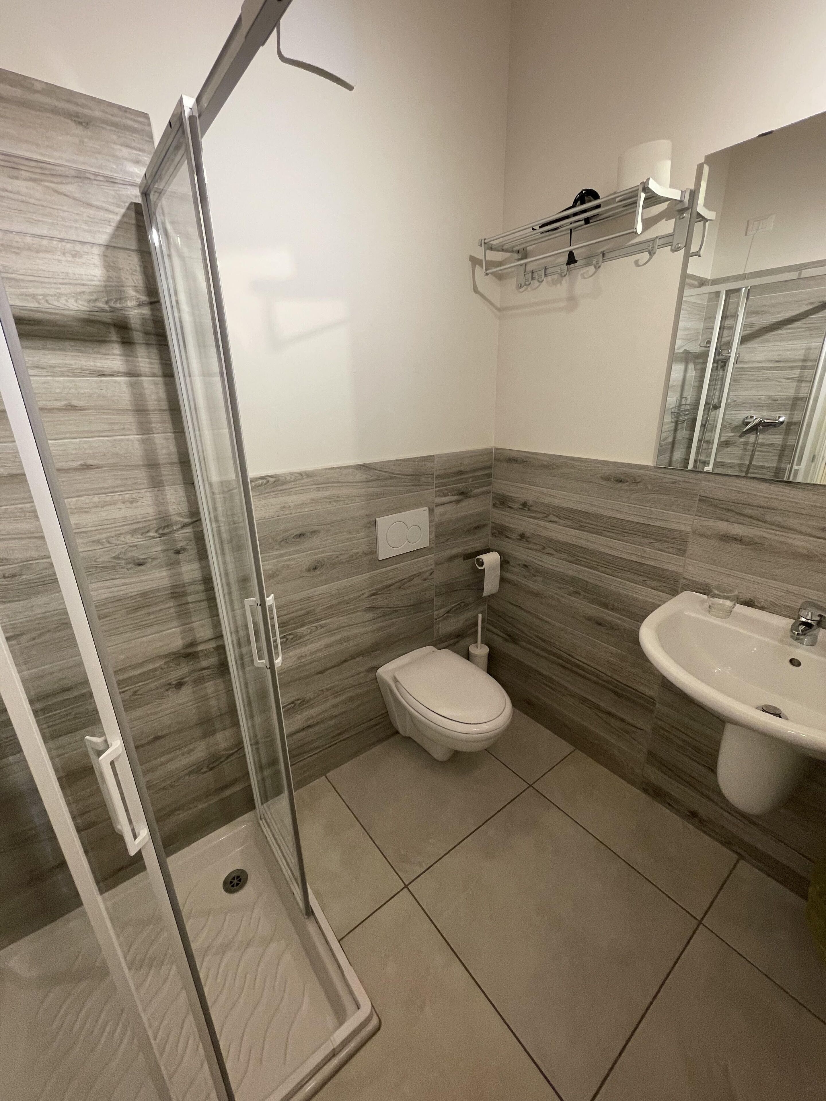 Un baño con cabina de ducha de vidrio, inodoro y lavamanos.