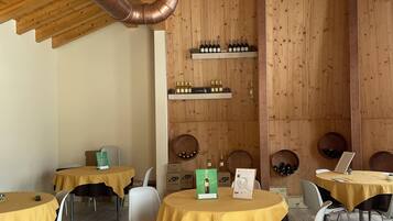 Un restaurante con paredes y techo de madera, mesas con manteles amarillos y botellas de vino en estantes.