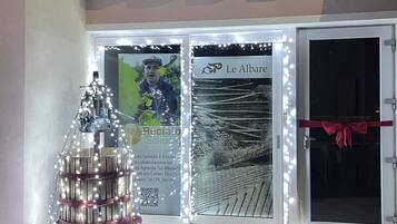 A building entrance with a large glass door, a red ribbon tied across the door, and a decorative light display in front.