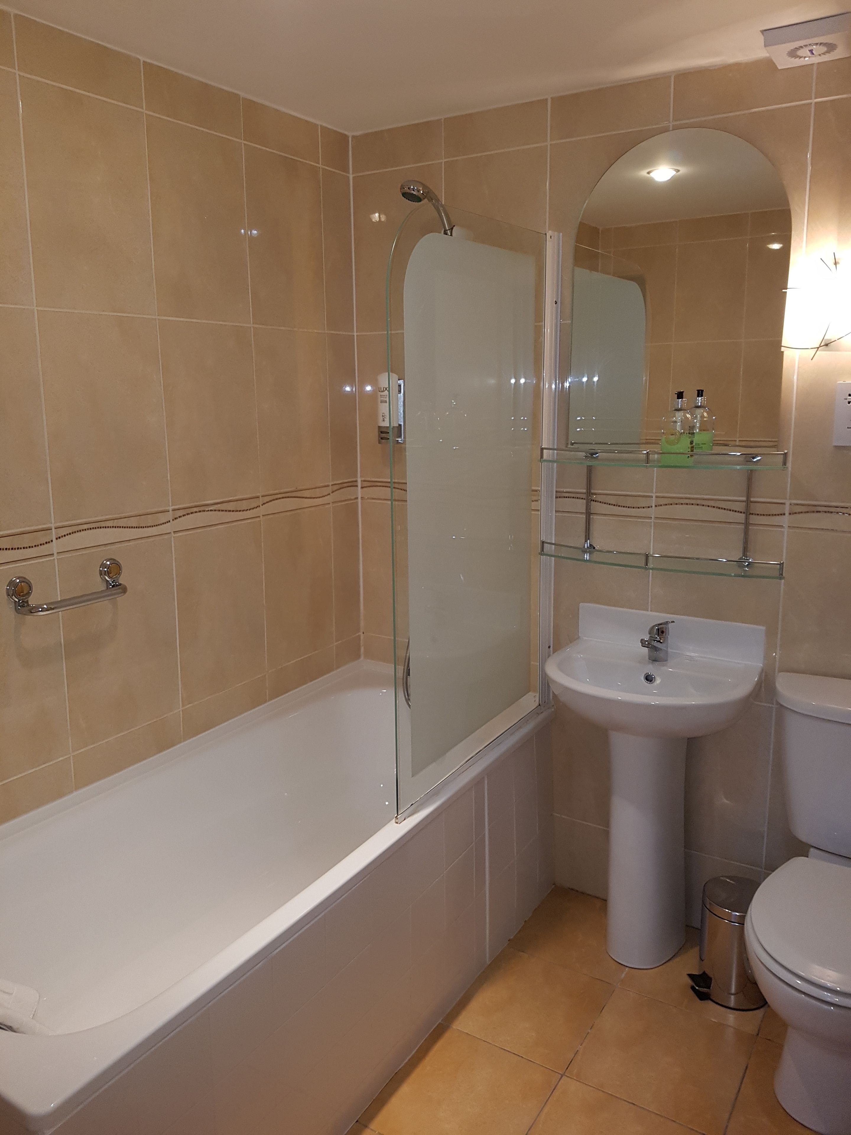 A bathroom with a bathtub, a glass-enclosed shower, a sink, and a toilet.