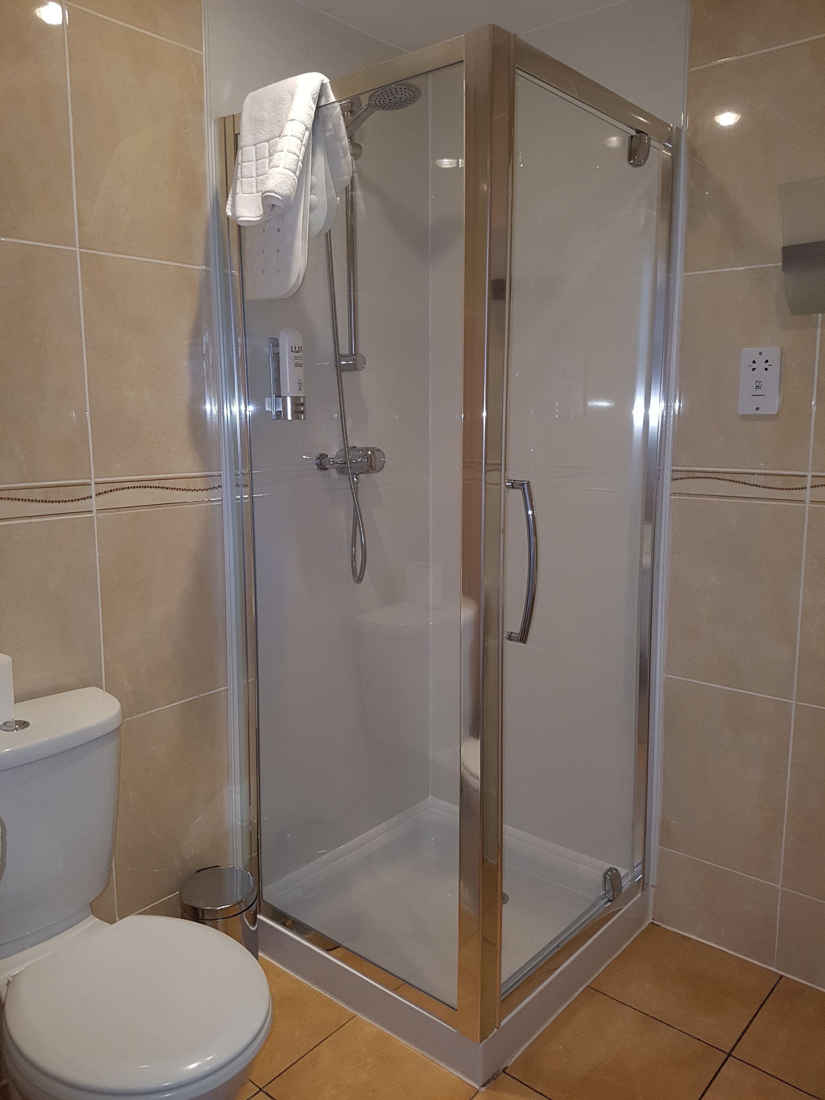 A modern bathroom with a glass-enclosed shower, a toilet, and a sink.