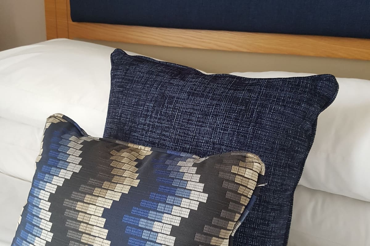 A bed with a white mattress and two decorative pillows.