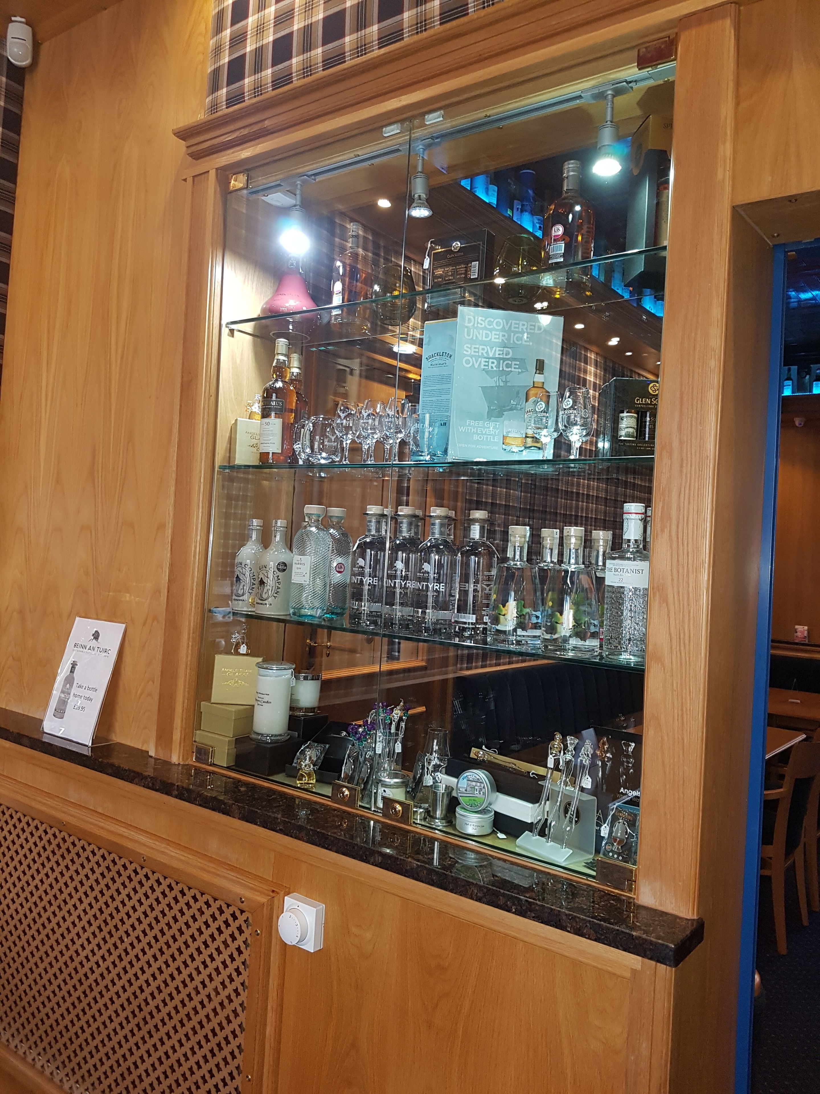 A bar area with shelves of liquor bottles and glasses, a sign offering a free gift with every bottle, and a menu board.
