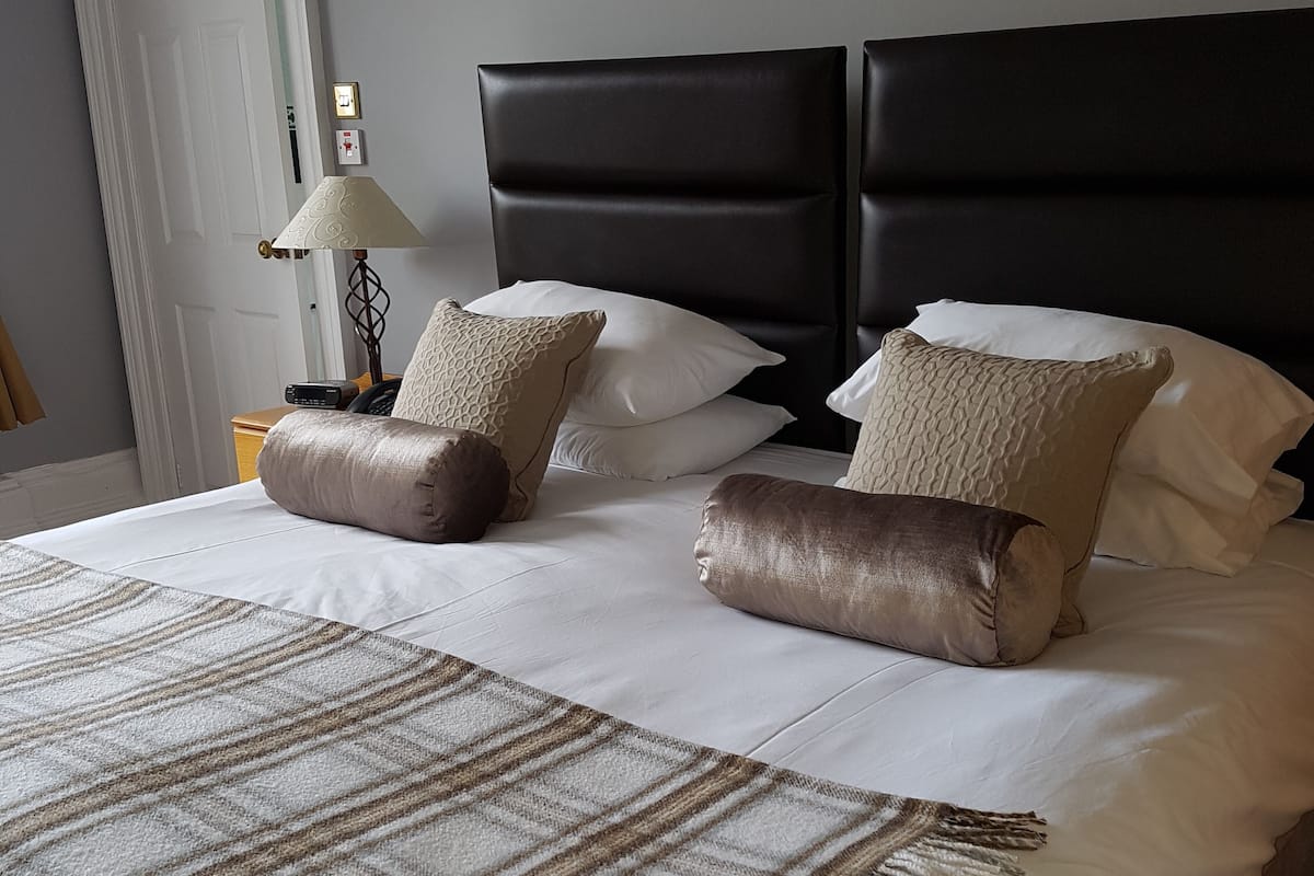 A neatly made bed with a striped blanket, two headboards, and several pillows.