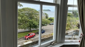 Una ventana con vista a una carretera, vegetación y una masa de agua.