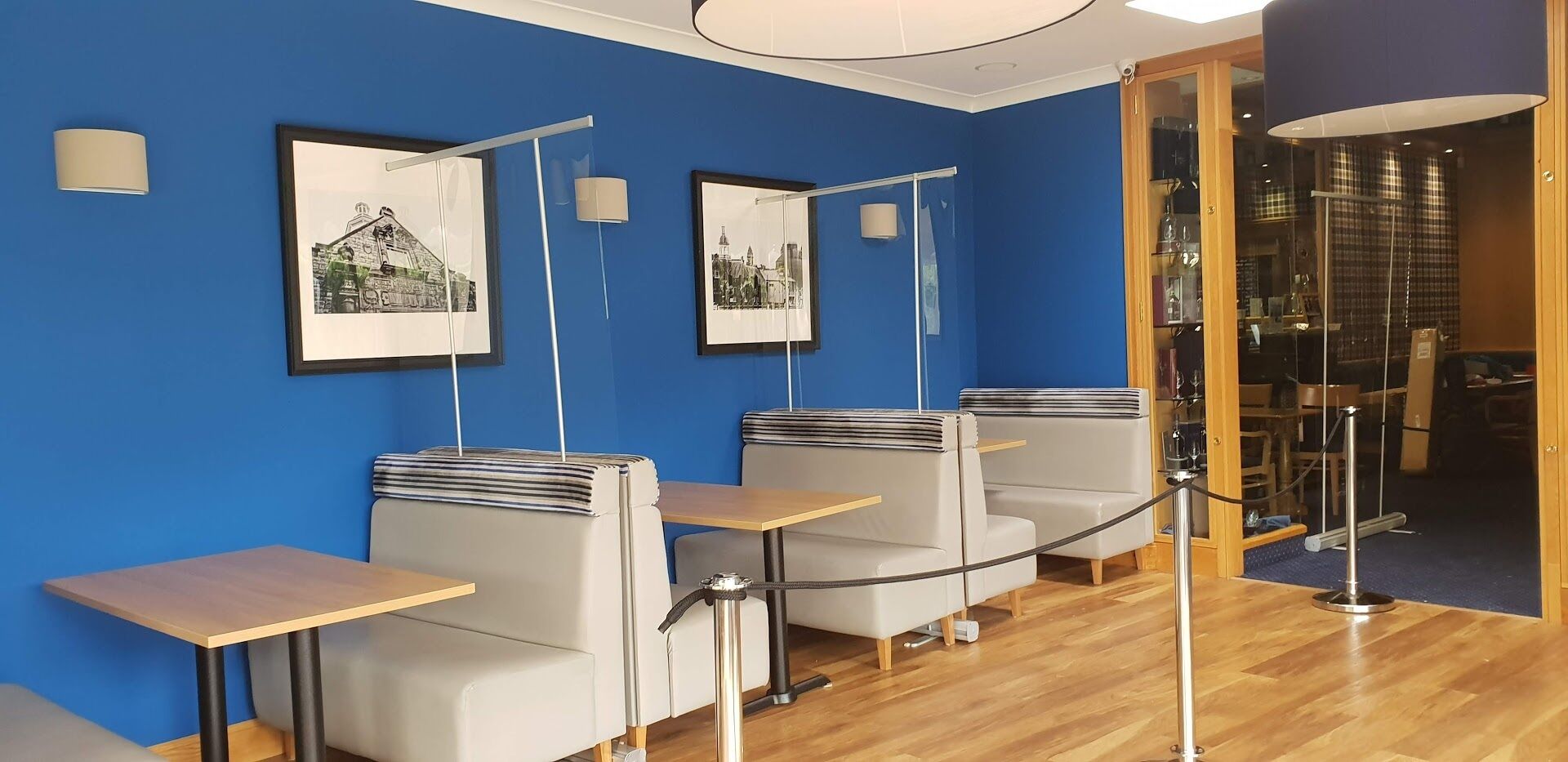 Habitación con paredes azules, cuadros enmarcados, una mesa de madera y una zona de estar con un separador de vidrio.