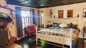 A cozy bedroom with a white metal bed frame, a red chair, and a vintage stove. - Little River Guest House (Gabrovo)