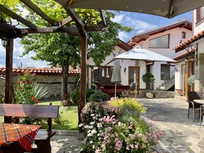 A courtyard with a pergola, outdoor seating, and a building with a tiled roof. - Iliikova House (Karlovo)