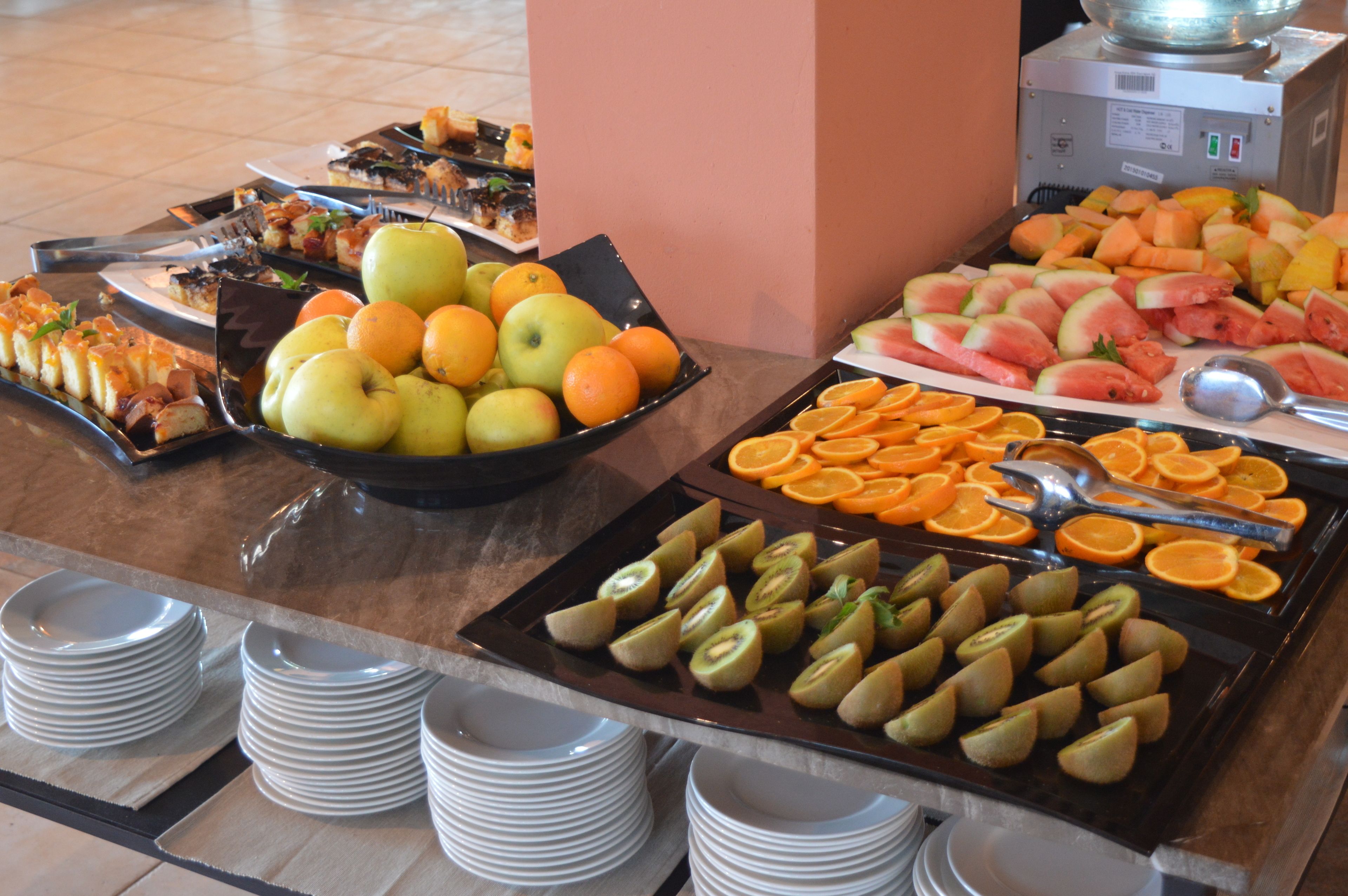 Ein Buffet mit verschiedenen Früchten und Gemüsesorten, darunter Äpfel, Orangen und Kiwischnitten.