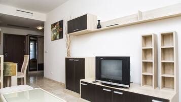 Una sala de estar moderna con un televisor de pantalla plana, armarios de madera y una mesa de centro de vidrio.