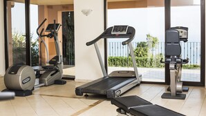 A home gym with a treadmill, elliptical, and stationary bike, large windows, and a view of the outdoors. - Kaliakria Resort (Kavarna)